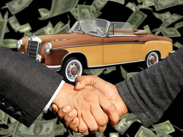 two people shaking hands in front of a potentially damaged used car